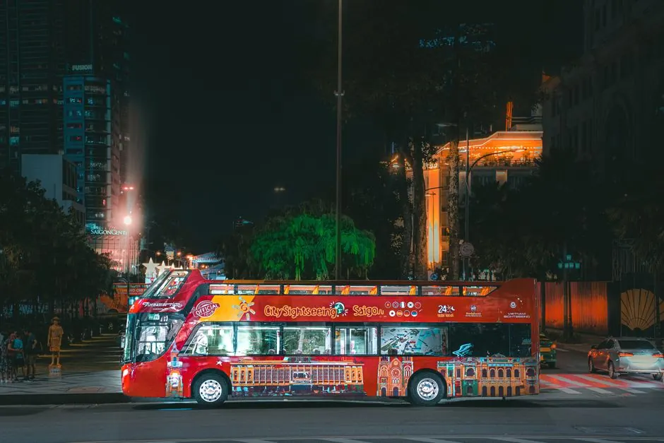 Vibrant red city sightseeing bus parked at night in an illuminated urban street.